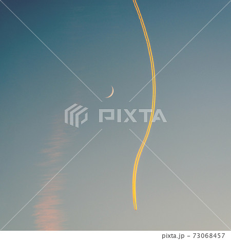 Jet airplane, its contrail and a crescent moon at sunset 73068457