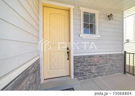 Front veranda of suburban home with a yellow door 73068804