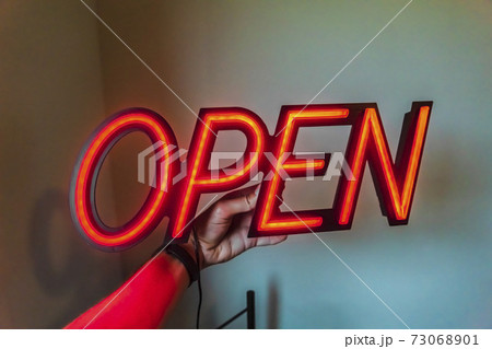 Person holding a glowing red Open sign 73068901