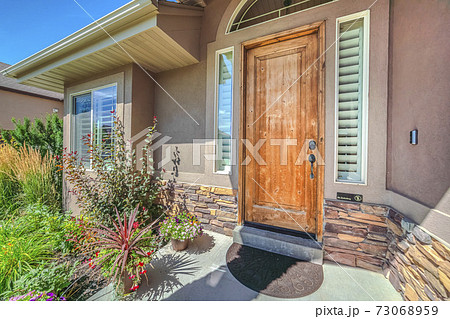 Front porch of house with wooden door and garden 73068959