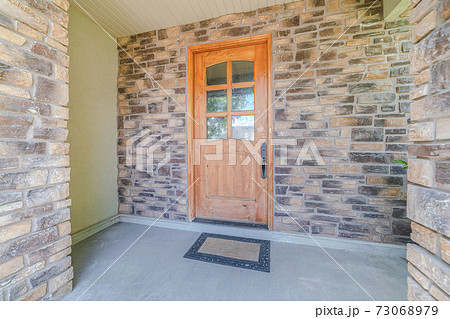Wooden front door of modern house with stone walls 73068979