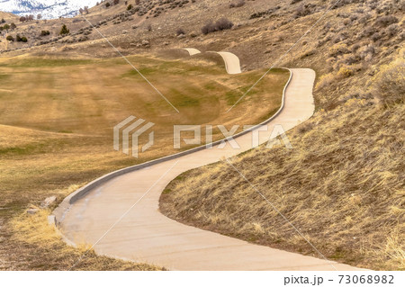 Winding narrow rural road through foothills golf Winding narrow rural road through foothills golf 73068982