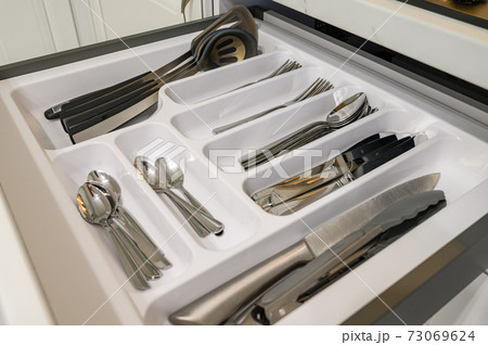 Open drawer with cutlery at modern white woden kitchen in classic style 73069624