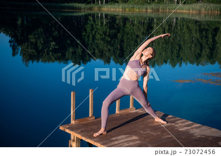 Girl is practicing yoga technique on the pier by the lake and meditating. Meditation to purify mind and calm. Girl is practicing yoga technique on the pier by the lake and meditating. Meditation to purify mind and calm. 73072456
