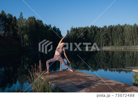 Beautiful young woman performing a spiritual yoga pose on a forest lake at sunny day, sunrise zen wellness Beautiful young woman performing a spiritual yoga pose on a forest lake at sunny day, sunrise zen wellness 73072488