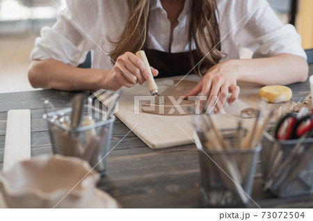 Female potters hand making clay pottery at the table with a different wooden tools close up. Female potters hand making clay pottery at the table with a different wooden tools close up. 73072504