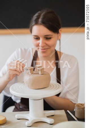 Woman decorating handmade pottery vase close-up 73072505