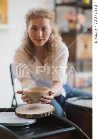 The female potter finished making a clay vase remove it from the potter's wheel. Creating vase of white clay. Making ceramic products from white clay, closeup The female potter finished making a clay vase remove it from the potter's wheel. Creating vase of white clay. Making ceramic products from white clay, closeup 73072533