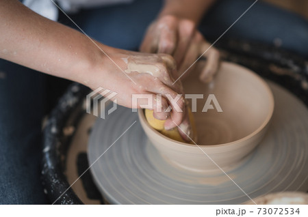 Potter makes the clay product with pottery modeling tools on the potter's wheel. Potter makes the clay product with pottery modeling tools on the potter's wheel. 73072534