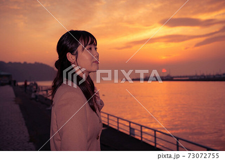 旅先の港で夕焼けを眺める女性 旅先の港で夕焼けを眺める女性 73072755
