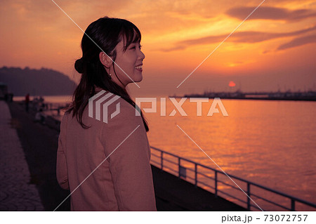 旅先の港で夕焼けを眺める女性 旅先の港で夕焼けを眺める女性 73072757