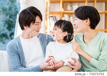 リビングでくつろぐ若い家族 73073702