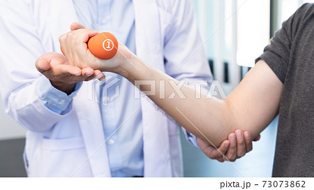 physiotherapist doctor rehabilitation consulting physiotherapy giving dumbbell exercising treatment with patient in physio clinic or hospital. 73073862
