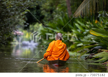 Buddhist monk in small wooden boat sailing in canal for receive food in morning, The culture tradition Buddhist monk of making merit to monks morning, Popular tourist attraction on canals of Thailand. 73075182