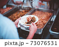 Homeless and needy people receive help, receive food from volunteers 73076531