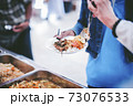 Homeless and needy people receive help, receive food from volunteers 73076533