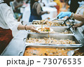 Homeless and needy people receive help, receive food from volunteers 73076535