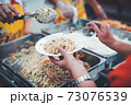 Homeless and needy people receive help, receive food from volunteers 73076539