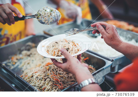 Homeless and needy people receive help, receive food from volunteers 73076539