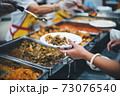Homeless and needy people receive help, receive food from volunteers 73076540