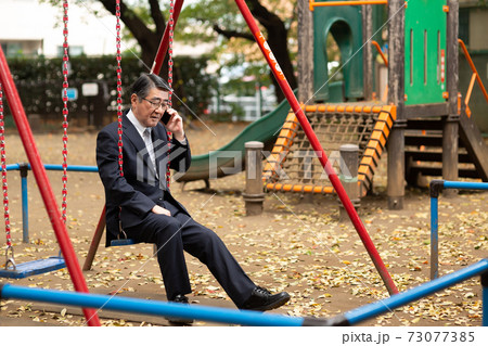 電話をするビジネスマン　公園ブランコ 73077385