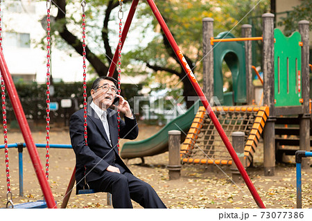 電話をするビジネスマン　公園ブランコ 73077386