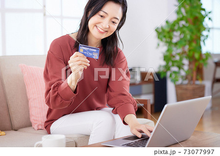 リビングでネットショッピングを楽しむミドルの女性 73077997