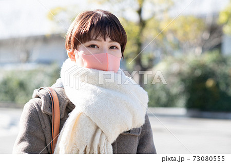 コートとマフラーとマスクを着用した冬の女性の写真素材
