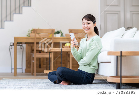 リビングでスマホを見る若い女性 73083395