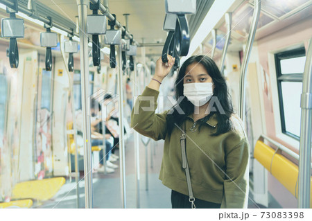 asian woman wearing protection mask standing in  city sky trains 73083398