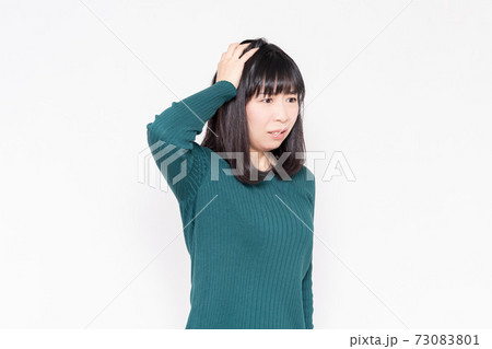 白背景の前に立っている頭を抱える女性 白背景の前に立っている頭を抱える女性 73083801