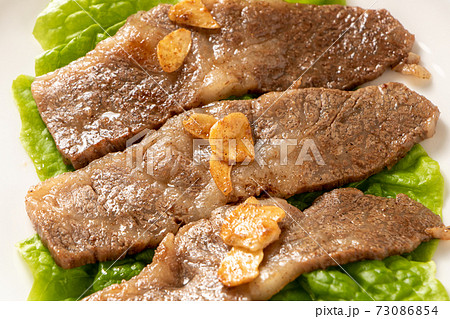 国産黒毛和牛カルビ焼肉。サンチュの上に盛り付け(にんにくチップのせ)。 国産黒毛和牛カルビ焼肉。サンチュの上に盛り付け(にんにくチップのせ)。 73086854