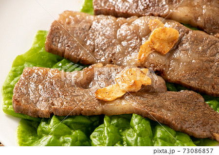 国産黒毛和牛カルビ焼肉 サンチュの上に盛り付け にんにくチップのせ の写真素材