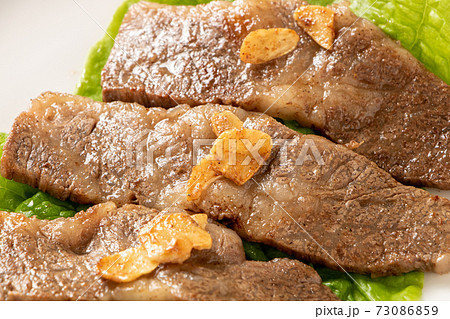 国産黒毛和牛カルビ焼肉。サンチュの上に盛り付け(にんにくチップのせ)。 国産黒毛和牛カルビ焼肉。サンチュの上に盛り付け(にんにくチップのせ)。 73086859