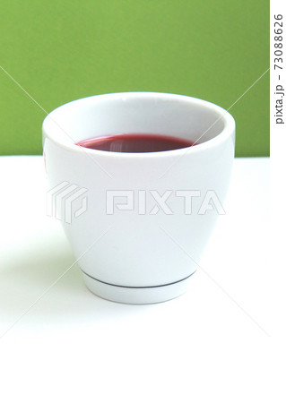 Red hibiscus tea in a white cup on green background Red hibiscus tea in a white cup on green background 73088626