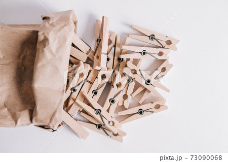 Wooden clothespins in paper bag on white background. View from above. Place for your text 73090068