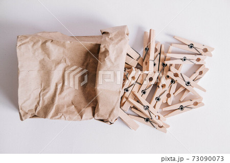 Wooden clothespins in paper bag on white background. View from above. Place for your text Wooden clothespins in paper bag on white background. View from above. Place for your text 73090073