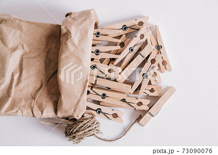 Wooden clothespins in paper bag with rope on white background. View from above. Place for your text 73090076