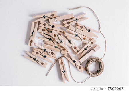 Wooden clothespins with rope on white background. View from above. Copy space 73090084