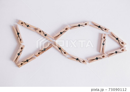 Wooden clothespins on a white background which are composed in the form of a fish icon. View from above. 73090112