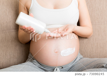 pregnant woman applying stretch mark cream to belly. pregnancy, people and maternity concept. pregnant apply anti-stretch mark cream on her belly pregnant woman applying stretch mark cream to belly. pregnancy, people and maternity concept. pregnant apply anti-stretch mark cream on her belly 73090245