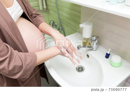 Correct way to wash hands concept. Caucasian pregnant woman washing and cleaning hands and fingers with soap and water. Pregnancy, maternity and bodycare concept 73090777