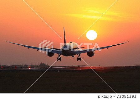 夕景の中着陸する飛行機 73091393