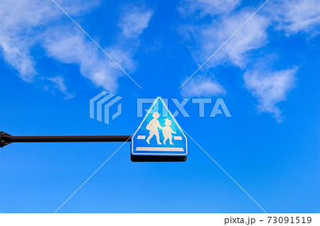 青空と子どもが通学で渡る横断歩道ありの標識 73091519