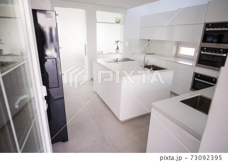 White organised kitchen with modern elements in an apartment White organised kitchen with modern elements in an apartment 73092395
