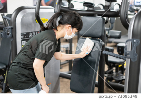 トレーニングジムのマシンを消毒する女性 73095349