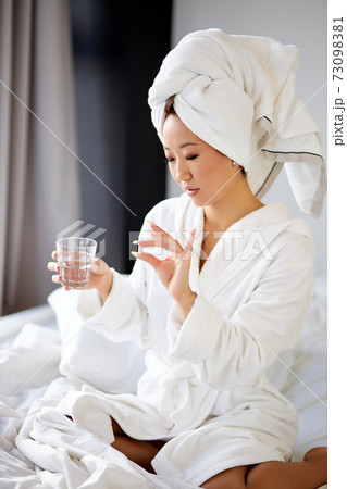 beautiful asian pregnant woman taking a medicine pill of vitamin while sitting on bed 73098381