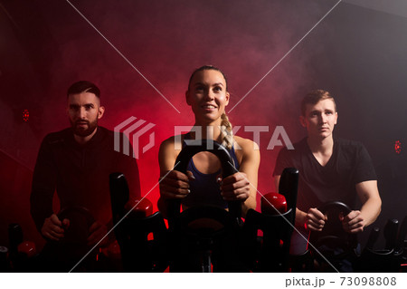 strong female is training with male sportsmen on bike maching in gym strong female is training with male sportsmen on bike maching in gym 73098808