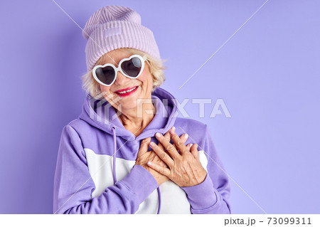 happy positive elderly woman holding hands on chest smiles happy positive elderly woman holding hands on chest smiles 73099311