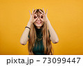 Making glasses fingers, looking at camera, smiling, funny, hold hands near eyes 73099447